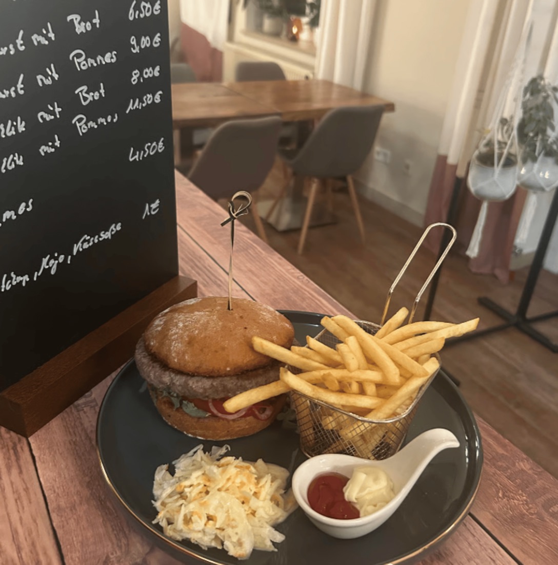 Charly's Classic Burger mit Pommes, Krautsalat und Dips auf einem Holztisch im Restaurant